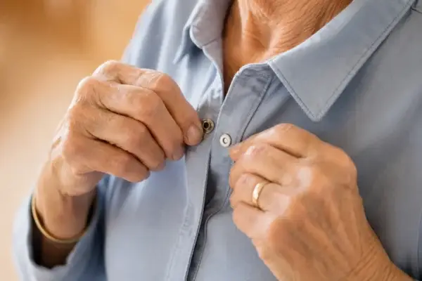 Magnetic closure shirt close-up 3 optimized Close-up of hands fastening a magnetic closure shirt with a ring visible